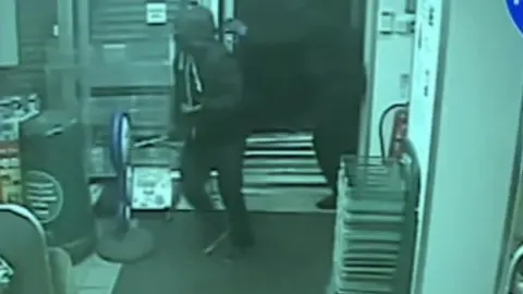 CCTV of men entering a shop during a raid