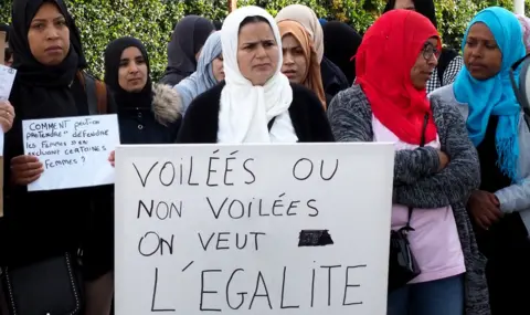 Getty Images Demonstrators outside a school in south-western France hold a placard reading: "Veiled or not veiled, we want equality" (28 May 2019)