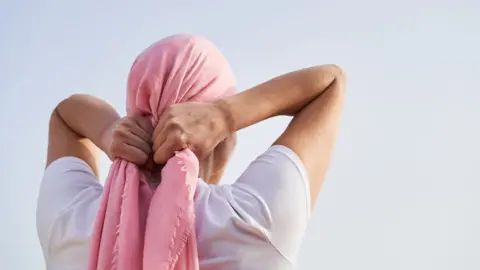 Getty Images Woman tying a headscarf