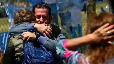 EPA A crying man holds a woman in an embrace outside the Mar del Plata base on 25 November