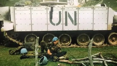 Family Handout Shaun Pinner lying in front of a tank with UN written on the side