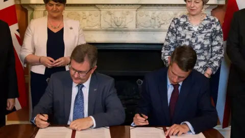 Reuters The deal was signed in Downing St by DUP MP Sir Jeffrey Donaldson and Tory Chief Whip Gavin Williamson