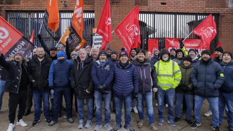 PA Media Striking workers on a picket line at Translink's Europa Bus Station in Belfast on Friday