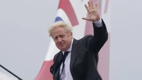 PA Media Boris Johnson waving as he boards a plane to New York