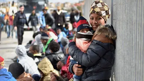 Getty Images Immigrants wait for a ferry in Lampedusa, southern Italy