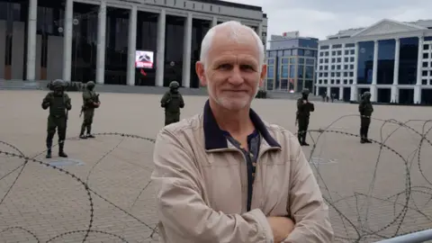 Ales Bialiatski/Facebook A Facebook picture of Ales Bialiatski standing in front barbed wire and armed Belarusian soldiers. Photo: September 2020