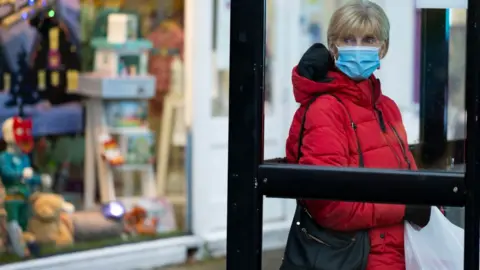 Getty Images Face masks will continue to be law in most places for months to come