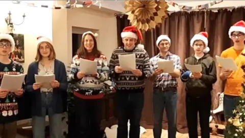 PA Media Kate Caroe's family choir singing Christmas carols