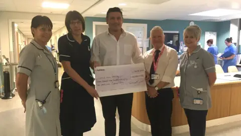 BBC Terry Garnett holding a giant cheque alongside hospital staff