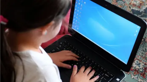 PA Media A child using a laptop computer