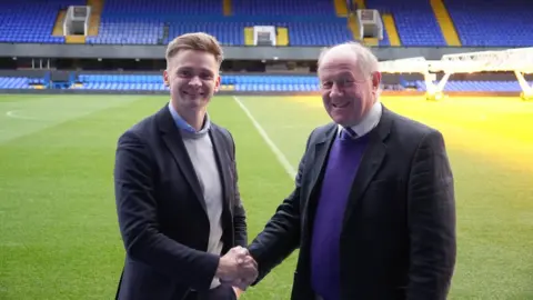 ITFC Foundation Head of the ITFC Foundation Dan Palfrey, shaking hands with Police and Crime Commissioner for Suffolk, Tim Passmore