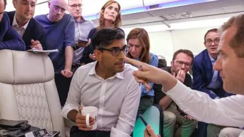 Getty Images Rishi Sunak on the plane to India speaking to reporters