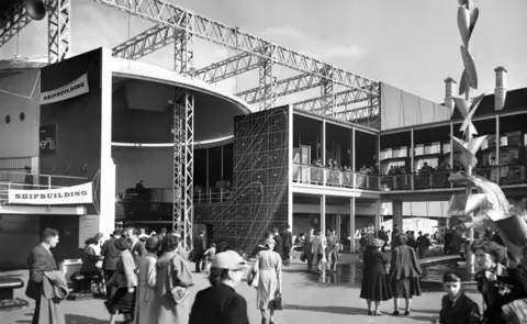 Historic England Archive Exterior view of part of the shipbuilding display at the Festival of Britain. On the left is the Power and Production Pavilion and on the right the Natural Resources Pavilion.