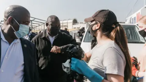 AFP via Getty Images President Cyril Ramaphosa interacts with volunteers who embark on a clean up campaign on July 16, 2021