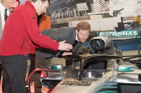 PA Prince Harry, studies the "Halo" on Lewis Hamilton"s Mercedes, a new safety addition to Formula 1 cars this year, during a visit to the Silverstone Circuit in Northamptonshire