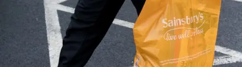 Getty Images customer walking with an orange Sainsbury's bag