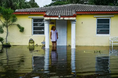 CHANDAN KHANNA/afp A woman looks on as she stands outside of her flooded home after heavy rain in Fort Lauderdale, Florida on April 13, 2023.