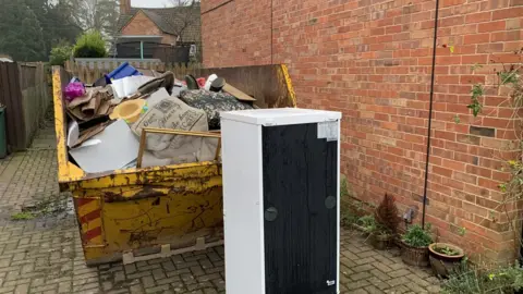 Damaged furniture in a skip outside