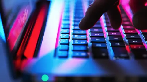 Getty Images A man's hand seen typing on a laptop keyboard