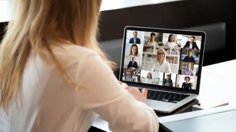 Getty Images Woman taking part in video conference with laptop showing several faces