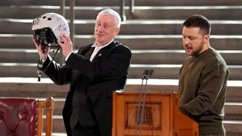 PA Media Speaker of the House of Commons, Sir Lindsay Hoyle (left), holds the helmet of one of the most successful Ukrainian pilots, inscribed with the words "We have freedom, give us wings to protect it", which was presented to him by Ukrainian President Volodymyr Zelensky as he addressed parliamentarians in Westminster Hall