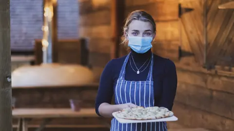 Getty Images Pizzeria waitress with mask on