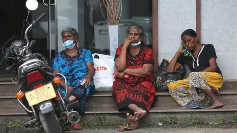 Getty Images People wait to buy kerosene oil at a petrol station in Colombo.