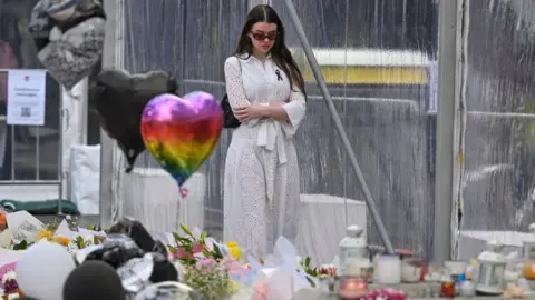 Getty Images A member of the community visits the flower memorial near the Bondi Junction Westfield