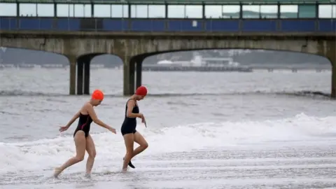 PA Media Two swimmers leaving the sea near Boscombe Pier