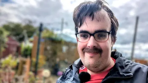 William Hendren wearing glasses and a moustache looking towards the camera.