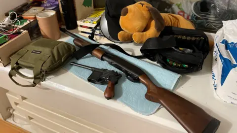 Sarah Rainsford Weapons lie beside a big stuffed toy on a family's window ledge