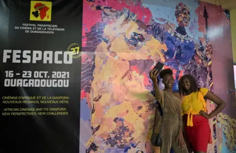 AFP Women take a selfie next to a poster.