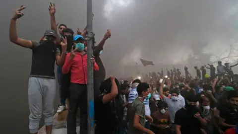 AFP Protesters pose amid smoke near a burning building in Basra, 6 September 2018