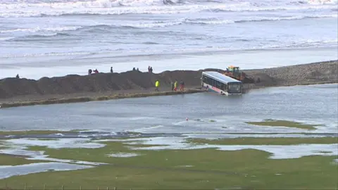 BBC A bus lies partially submerged in water after Newgale is battered by storms in 2014