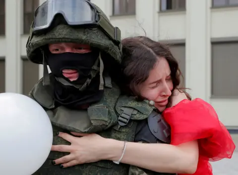 Vasily Fedosenko / Reuters A woman embraces a member of the Belarusian interior troop near the Government House in Independence Square in Minsk, Belarus, 14 August 2020