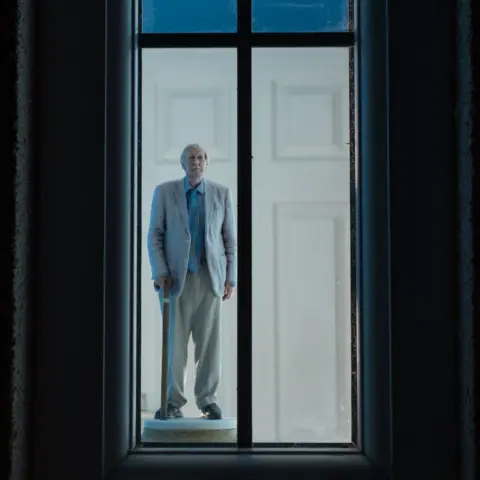 Wendy Aldiss A man stands looking out of a window