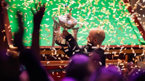 Getty Images Luca Brecel of Belgium holds the trophy at the 2023 Cazoo World Championship at Crucible Theatre on 1 May 2023 in Sheffield, England