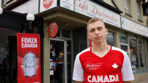 Getty Images Alistair Johnson, part of the Canadian football team headed to Qatar, poses outside a send-off event for the team at Toronto's Cafe Diplomatico in Little Italy