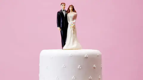 Getty Images A bride and groom model on top of a wedding cake