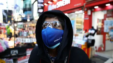 Getty Images A man wear mask to prevent the coronavirus (COVID-19) walk along the Myungdong shopping district on February 23, 2020