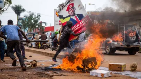 Getty Images A supporter of Ugandan musician turned politician Robert Kyagulanyi, also known as Bobi Wine, carries his poster as they protest on a street against the arrest of Kyagulanyi