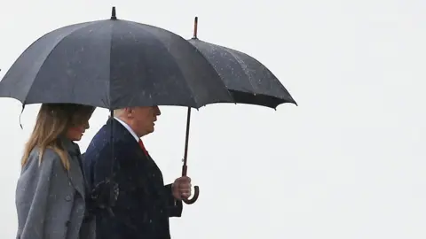 Getty Images Donald and Melania Trump are pictured under umbrellas walking to the Armistice Ceremony at the Arc de Triomphe, Paris