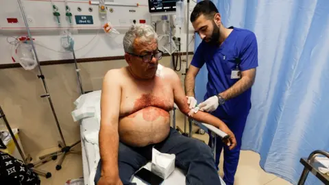 Reuters A Palestinian journalist receives treatment in hospital after being shot during an Israeli raid in Jenin (11 May 2022)