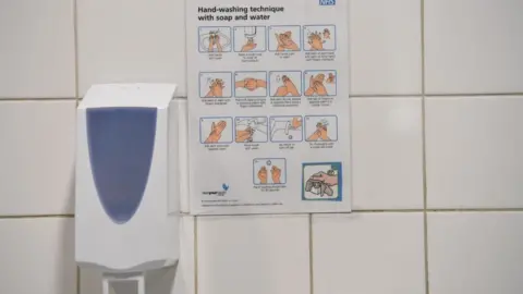 EPA An NHS sign depicting how to wash your hands is on display in a public toilet