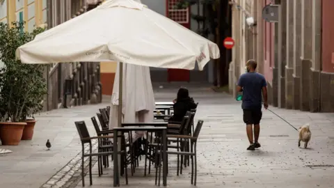 EPA A man walks his dog along a street in Santa Cruz de Tenerife, Canary Islands, Spain