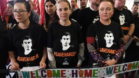 AFP/Getty Images Supporters at the airport hold up 'Welcome Home' signs