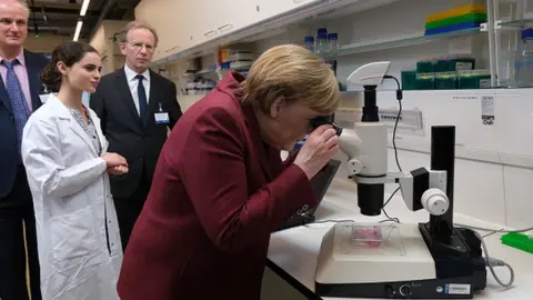 Getty Images German Chancellor Angela Merkel looks through a microscope