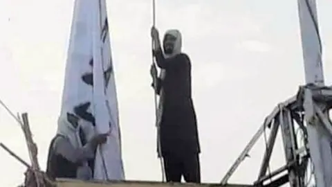 Twitter A social media image showing a man raising a Taliban flag