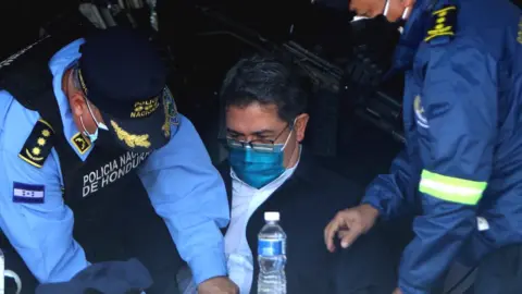 Honduran former President Juan Orlando Hernández (C) is handcuffed at the headquarters of the Honduras Police, 15 February 2022