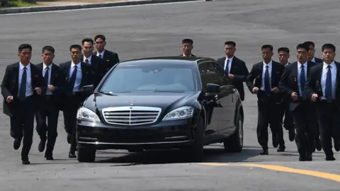 Getty Images Bodyguards run alongside a car carrying North Korean leader Kim Jong-un as he returns to the North for a lunch break following a morning session of the inter-Korean summit in Panmunjom, 27 April 2018